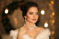 Elegant woman in white fur. Winter fashion portrait of Beautiful bride young with diamond earrings and necklace jewelry set.