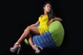 Elegant woman in a yellow dress posing lying on bean bag on a black background