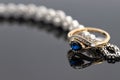 An elegant women`s gold ring with blue saphire is placed on a bracelet with precious stones