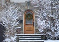 Front door with Christmas wreath and snow covered trees Royalty Free Stock Photo