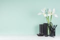 Elegant workplace with black stationery, books, fresh white iris bouquet on green mint menthe wall and white wood table.