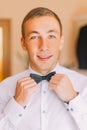 Elegant young business man posing fixing his black bowtie Royalty Free Stock Photo