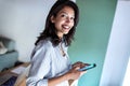 Elegant young business woman looking at camera while sending a phone message in the office Royalty Free Stock Photo