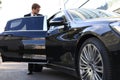 Elegant young businessman entering his car while standing outdoors