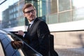 Elegant young businessman entering his car while standing outdoors