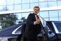 Elegant young businessman entering his car while standing outdoors