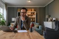 Elegant young businessman with hand on chin thinking while working over laptop on desk at home Royalty Free Stock Photo