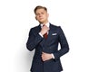 Elegant young businessman, student, diplomat straightens his tie isolated on white studio background. Human emotions