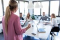 Elegant young businesswoman explaining a new project to her colleagues on coworking place. Back view Royalty Free Stock Photo