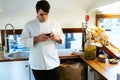 Elegant young chef using his mobile phone in a food truck.
