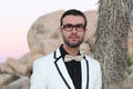 Elegant young fashion man with glasses in tuxedo shot at sunset in Joshua Tree National Park, California, USA