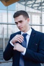 Elegant young fashion man looking at his cufflinks while fixing them