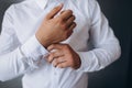 elegant young fashion man looking at his cufflinks while fixing them. Royalty Free Stock Photo