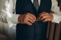 elegant young fashion man looking at his cufflinks while fixing them. Royalty Free Stock Photo