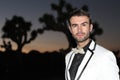 Elegant young fashion man in tuxedo shot at sunset in Joshua Tree National Park, California, USA