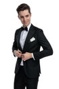 Elegant young groom in tuxedo looking to side and arranging coat Royalty Free Stock Photo