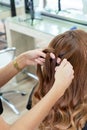 Elegant young hairdresser molds the hair with her hands to a red hair client`s with in a modern hairdressing salon Royalty Free Stock Photo