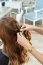 Elegant young hairdresser molds the hair with her hands to a red hair client`s with in a modern hairdressing salon Royalty Free Stock Photo