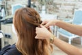 Elegant young hairdresser molds the hair with her hands to a red hair client`s with in a modern hairdressing salon Royalty Free Stock Photo