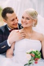 Elegant young happy wedding couple is sitting at green grass on Royalty Free Stock Photo