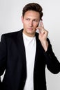 Elegant, young man in a business suit, standing on a white background and talking on a mobile phone Royalty Free Stock Photo