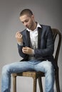 Elegant young man in sitting on a stool while buttoning his sle Royalty Free Stock Photo