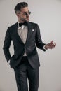 Elegant young man in tuxedo looking to side and making a hand gesture Royalty Free Stock Photo