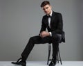 Elegant young man in tuxedo sitting on metal chair Royalty Free Stock Photo