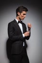 Elegant young man wearing tuxedo and fixing his sleeve Royalty Free Stock Photo