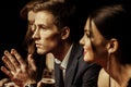 Elegant young people drinking alcohol and looking away on black