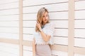 Elegant young woman in a fashionable beige skirt in a white lace blouse with an ornament is standing near a vintage white wall Royalty Free Stock Photo