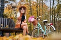 Stylish woman with bicycle drinking coffee in autumn park. Royalty Free Stock Photo