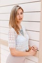 Elegant young woman in a white lace blouse with a stylish beige skirt with a luxurious shiny necklace posing near vintage wall Royalty Free Stock Photo