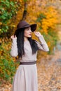 Elegant young woman in wide-brimmed hat gracefully poses with poise in scenic autumn park Royalty Free Stock Photo