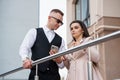 Elegantly Dressed Couple Engaged in Conversation on a Modern Staircase Royalty Free Stock Photo