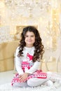 Elegantly dressed curly girl with delight admires gold Christmas garlands magic lights and tree decorations Royalty Free Stock Photo