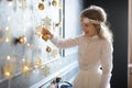 Elegantly dressed girl of 8-9 years with delight touches gold Christmas garlands Royalty Free Stock Photo