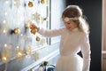 Elegantly dressed girl of 8-9 years with delight touches gold Christmas garlands Royalty Free Stock Photo