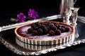 an elegantly presented blackberry tart on a silver tray