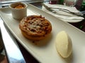 Elegantly served round shaped small single apple pie and vanilla mousse