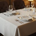 Elegantly set dining table with white linen tablecloth, featuring subtle embroidered patterns. Royalty Free Stock Photo