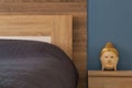 Element of bedroom interior with classic blue color wall, cozy bed and decoration buddha on bedside table