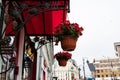 Element of urban landscape. Wrought-iron bronze canopy pattern over the door, bright red roof and flowers in hanging pots