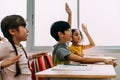 Elementary age Asian student boy raised hands up in Q and A classroom. Diverse group of pre-school pupils in elementary Royalty Free Stock Photo