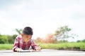 Elementary age boy writing in book while lying down on floor. Royalty Free Stock Photo