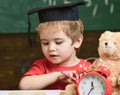 Elementary education concept. First former with toy on desk, close up. Pupil in mortarboard, chalkboard on background