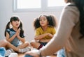 Elementary international students sitting on floor in circle around the teacher and listening a story in their classroom.The Royalty Free Stock Photo