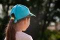 Elementary school age child, girl looking at something, seen from behind, copy space, back of the head closeup baseball cap