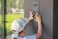 Elementary school age child, girl using a door entry phone, entering the entry code alone outdoors, block of flats