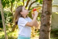 Elementary school age girl playing a toy trumpet prop, holding it in hands doing a bugle call signal. Simple calling, call to arms